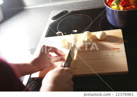Hands cutting garlic on a wooden cutting board 12376961
