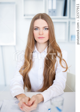 Portrait of beautiful young business woman sitting at desk in br 12377911