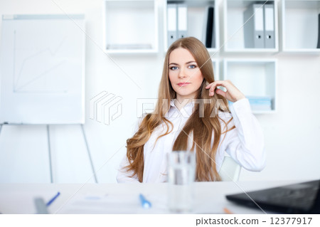 Portrait of beautiful young business woman sitting at desk in br 12377917