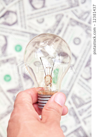 hand holding eco light bulb on dollars background 12381437