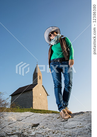 Posing young woman in a stylish hat and an old romanesque church 12386380