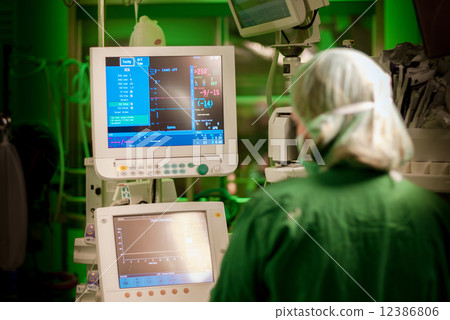 female anesthesiologist at monitor in operation surgery room with green lights on 12386806