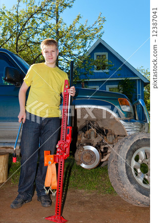 The young man, the teenager replaces a wheel at an off-road car.. 12387041
