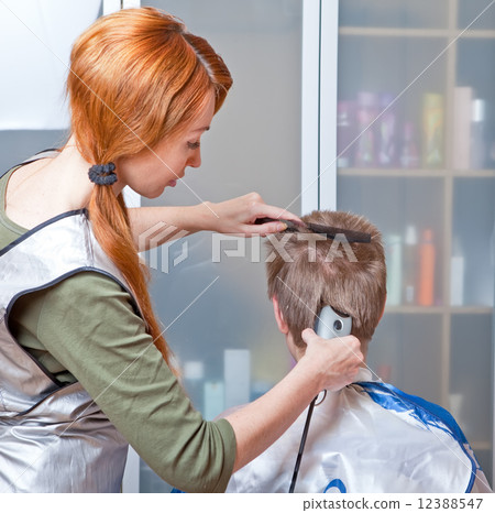 The beautiful young woman the hairdresser does a  hairstyle to the client - young man 12388547