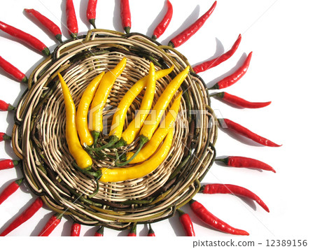 Red and yellow chili peppers on a wicker stand 12389156