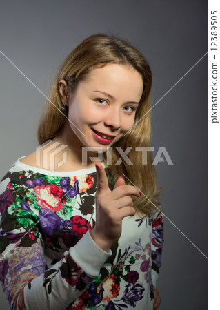 Beautiful blond young woman threatens forefinger and smiling 12389505