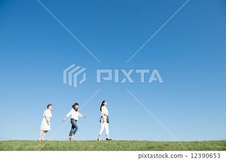 Women walking along the grassland 12390653
