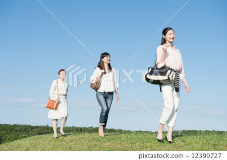 Women walking along the grassland Women walking along the grassland 12390727