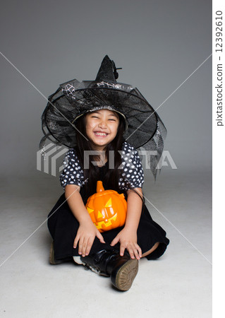 Portrait of little Asian girl in black hat and black clothing with pumpkin Portrait of little Asian girl in black hat and black clothing with pumpkin 12392610