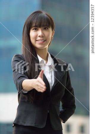 One successful young chinese business woman in front of office building giving welcome handshake One successful young chinese business woman in front of office building giving welcome handshake 12394357