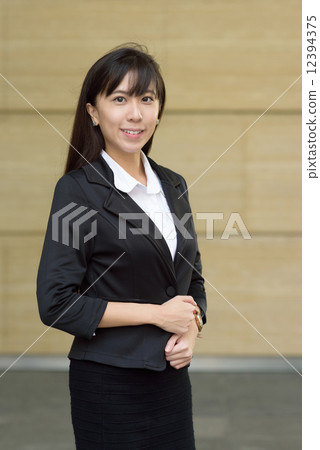 Portrait of one successful young chinese business woman in front of yellow marble wall 12394375