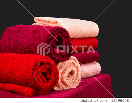 stack of colorful terry towels on a table isolated on dark background 12396608