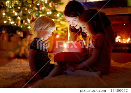 Mother and her daughters opening a Christmas gift 12400032