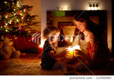 Happy family by a fireplace on Christmas 12400060