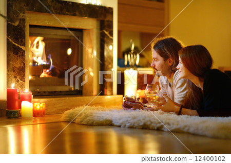 Happy couple by a fireplace on Christmas Happy couple by a fireplace on Christmas 12400102