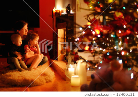 Young mother and her daughters by a fireplace 12400131
