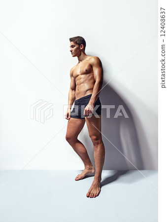 Muscular man leaning to white wall Muscular man leaning to white wall 12408637