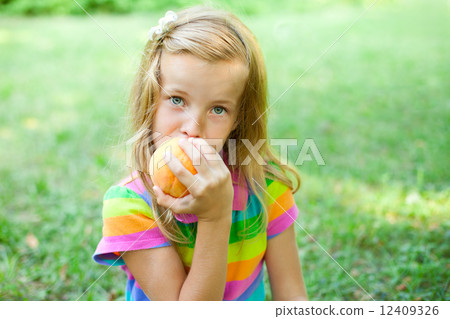 Little girl eating peach in the park 12409326