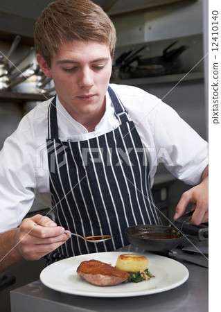 Male Chef Preparing Meal In Restaurant Kitchen Male Chef Preparing Meal In Restaurant Kitchen 12410140