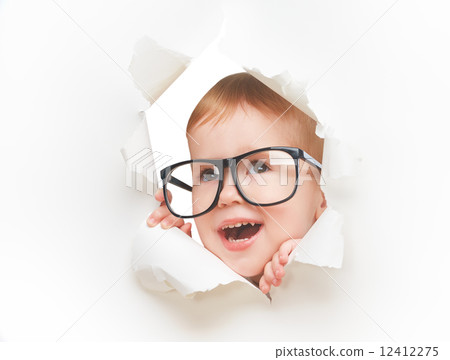 Funny child baby girl with glasses peeping through hole in an empty white paper Funny child baby girl with glasses peeping through hole in an empty white paper 12412275