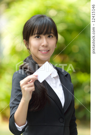 One successful young chinese business woman showing her business name card in front of greenery 12415146