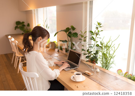 A woman using a laptop computer at a cafe 12418358