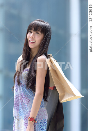 Young chinese woman shopping with shopping bags standing outside of mall along promenade Young chinese woman shopping with shopping bags standing outside of mall along promenade 12423616