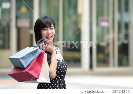 Young chinese woman shopping with shopping bags standing outside of mall along promenade Young chinese woman shopping with shopping bags standing outside of mall along promenade 12424243