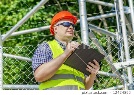 Worker with folder near the fence Worker with folder near the fence 12424893