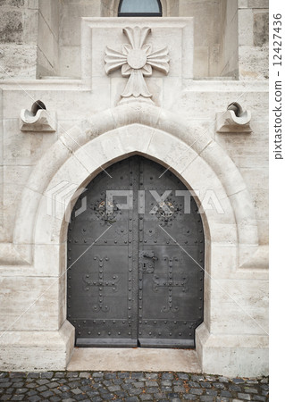 black ancient metallic door in old stone wall 12427436
