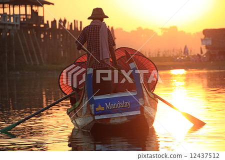 Burmese boatman and buddhist novice sitting in boat 12437512