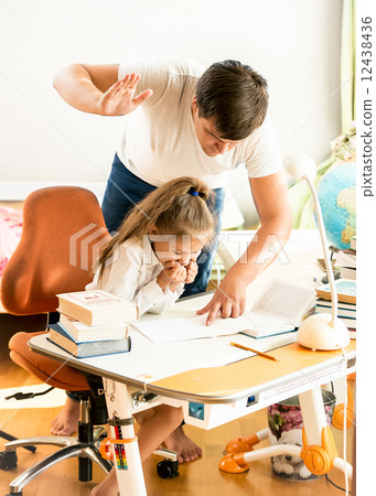 man giving a cuff on nape to daughter doing homework 12438436