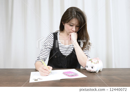 A young housewife who writes household account book with a difficult face 12440072