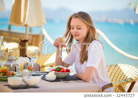 Woman eating fruits in a beach restaurant Woman eating fruits in a beach restaurant 12443727