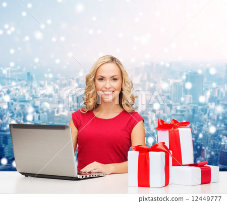 smiling woman in red shirt with gifts and laptop 12449777