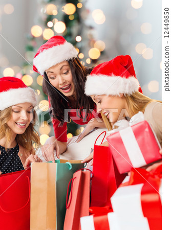 smiling young women in santa hats with gifts 12449850