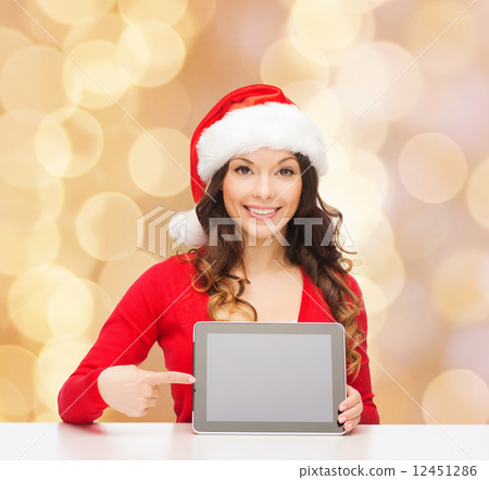 smiling woman in santa hat with gift and tablet pc smiling woman in santa hat with gift and tablet pc 12451286
