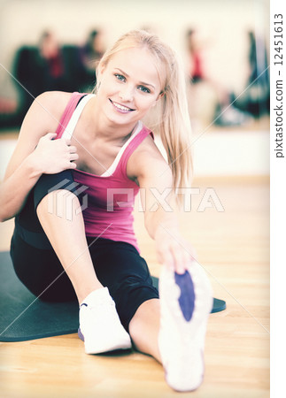 smiling woman stretching on mat in the gym smiling woman stretching on mat in the gym 12451613