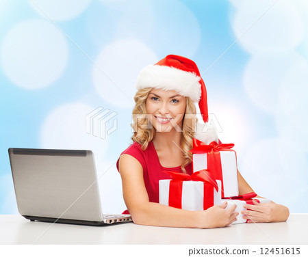 smiling woman in santa hat with gifts and laptop smiling woman in santa hat with gifts and laptop 12451615