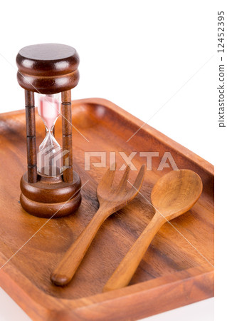 Hourglass on a plate with a fork and knife for food and time con 12452395
