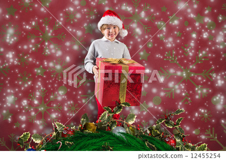 Composite image of festive boy holding gift 12455254