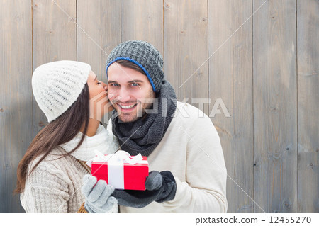 Composite image of winter couple holding gift 12455270