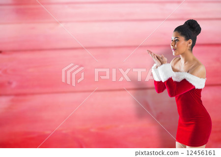 Composite image of pretty santa girl blowing over her hands Composite image of pretty santa girl blowing over her hands 12456161