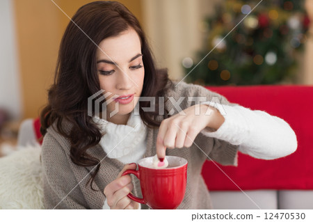 Brunette dunking marshmallow in hot chocolate at christmas Brunette dunking marshmallow in hot chocolate at christmas 12470530