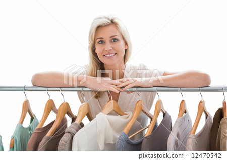 Pretty blonde smiling at camera by clothes rail 12470542