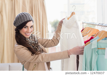 Smiling shopping brunette looking at dress Smiling shopping brunette looking at dress 12470837