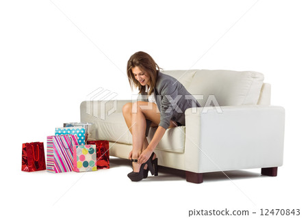 Cute woman sitting on couch taking off her shoes Cute woman sitting on couch taking off her shoes 12470843