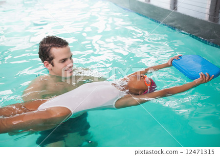 Cute little girl learning to swim with coach 12471315