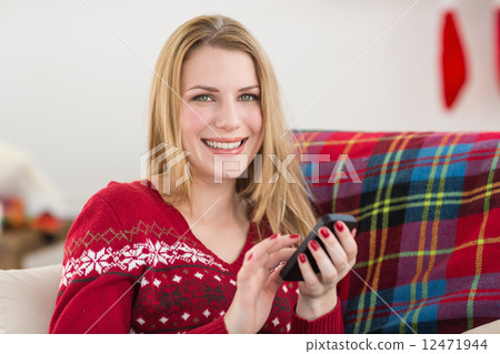 Pretty blonde sitting on the couch texting on the phone 12471944