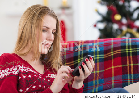 Pretty blonde sitting on the couch texting on the phone 12472114